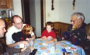 Grandpa Dave plays cards with grandchildren Samantha and Stevie Hanneman while Joe and David Hanneman look on.